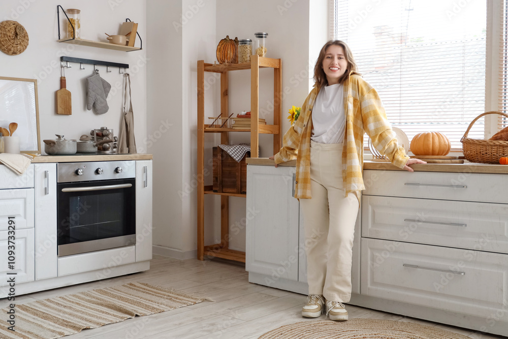 Young woman near counters in kitchen on autumn day