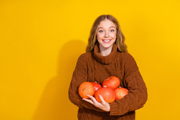 Wall Mural - Portrait of nice young girl hold pumpkins empty space wear sweater isolated on yellow color background