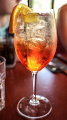 Close-up of a refreshing mimosa cocktail with orange slice garnish on a vibrant red table surface