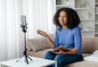 © Anastasiya - Modern Bloger. Black Female Influencer Recording Video For Her Vlog At Home, Smiling Young African American Woman Using Smartphone On Tripod, Talking And Gesturing At Camera, Closeup Shot. High