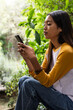 © Wavebreak Media - asian female teenager using smartphone outdoors, focusing on screen in peaceful garden setting