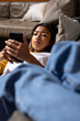 © Wavebreak Media - Asian female teenager relaxing on couch, focused on smartphone at home