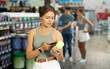 © JackF - Girl scans QR code with her phone to check product information. Buying cans of aerosol paint at hardware store