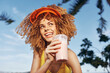 © SHOTPRIME STUDIO - Happy young woman enjoying a refreshing pink smoothie on a sunny day Bright colors and tropical background create a cheerful atmosphere