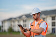 © Volodymyr - Engineer with tablet, building inspection. Serious engineer at new home. Construction manager in helmet. Architect at a construction site. Handyman builder in hardhat. Building concept.