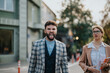© qunica.com - A man and woman in business attire walk happily outdoors, with one making a funny face. Capturing the fun side of professional life in a city setting.