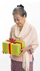 Elderly woman in traditional attire holding a wrapped gift with a red ribbon