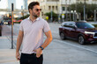 © Volodymyr - Stylish man wearing sunglasses and shirt. Handsome man outdoors portrait. Portrait of stylish male model outdoor. Fashion male posing near skyscraper on the street. Fashionable man in urban style.