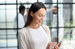 © Katsiaryna - Businesswoman with phone in modern office