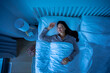 © Home-stock - Young woman lying on back, sleeping cozily on bed at night, bedroom with blue light shining through the window, top view shot, free space