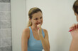 © romaset - Young woman in a modern bathroom washing her face and brushing her teeth