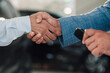 © Zamrznuti tonovi - Handshake between two people at a car dealership, sealing a deal.