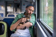 © DimaBerlin - Caring man comforts, hugging nervous cat from carrier, pet on lap watching out window in train car. Animal shows signs of anxiety, male owner strokes gently, easing travel stress. Travelling with pet.