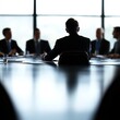 © Chanida - Silhouette of a businessman in a meeting around a conference table.
