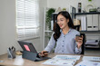 © Wasana - Businesswoman is working from her office, using a digital tablet and drinking coffee