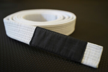 White Brazilian Jiu Jitsu belt, blur background. Concept of initiation and principles in martial arts.