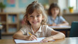 © dapra01 - A cute, successful primary school learner sitting at a desk during a lesson, looking directly at the camera with a bright smile