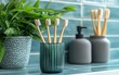 © Nattapat - Minimalist ecofriendly bathroom accessories green glass toothbrush holder, bamboo toothbrushes, and modern gray jar on blue and white tile background