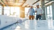 © PStyle - Engineers and Architects Collaborating Over Construction Plans in a Bright Office Space