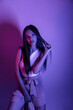 © FATIR29 - High Fashion model woman in colorful bright neon blue and purple lights posing in studio. Portrait of beautiful woman with trendy glowing make-up. Art design vivid style