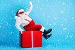 © deagreez - Full length photo of fat overweight santa claus with big stomach beard sit red gift box greeting x-mas christmas party wear suspenders overalls sunglass isolated blue color background