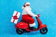 © deagreez - Full body profile side photo of stylish modern white grey hair bearded santa claus drive scooter deliver x-mas time eve gift box wear suspenders overalls isolated blue color background