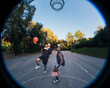 © Studio Marmellata - basketball player goes for a layup on an outdoor court surrounded by greenery, highlighting motion and skill with other players in the background under soft sunlight and clear skies