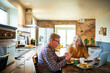 © Marko Geber - Senior couple eating breakfast with laptop on kitchen table