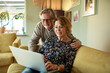 © Marko Geber - Senior couple online shopping on laptop on the couch at home