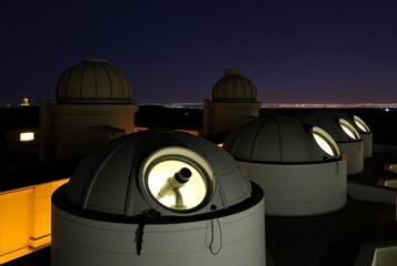 _ - Observatory rooftops with circular windows lit to reveal tel