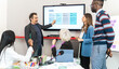 © Lomb - Diverse business team discussing content planning strategy with senior manager presenting weekly timeline on screen