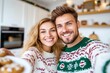 © Natalia - Couple enjoys cozy holiday moments in matching sweaters while taking a selfie in a warm kitchen