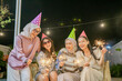 © Odua Images - Four friends joyfully celebrate a vibrant night with sparklers and colorful party hats