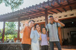 © Odua Images - potrait of happy asian family standing in front of the house with waving hand gesture