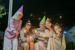 © Odua Images - Friends in colorful party hats enjoy a festive night with sparklers, creating a lively vibe