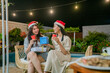 © Odua Images - Two great friends are joyfully enjoying a festive outdoor gathering filled with holiday cheer