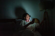 © Odua Images - A person is found enjoying their time on a mobile phone in a cozy and dimly lit bedroom space