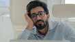 © Yuliia - Sleepy tired Arabian Indian man businessman lazy worker employee manager working boring online job in office feel depression burnout low energy apathy fatigued overwork unwell male guy with weariness