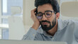 © Yuliia - Tired lazy Indian man Arabian businessman manager bored yawn at office desk boring computer work online low energy burnout sleeping exhausted tired male business entrepreneur laptop working boredom