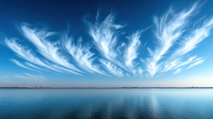 Wall Mural - Wispy clouds reflected on calm lake water at dawn.