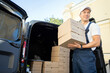 © muse studio - Delivery worker unloading boxes from van in bright daylight outside a commercial building
