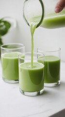 Canvas Print - Celery juice being poured into three transparent glasses on a light background in a high-resolution setting