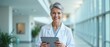 © schiers_images - Confident medical professional smiling while holding a digital tablet in a contemporary office setting. This image captures expertise, technology use, and a welcoming healthcare environment.