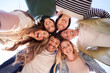 © CarlosBarquero - Selfie portrait from below of diverse generation z group friends posing smiling in circle looking at camera outdoor. Happy multiracial young people having fun embracing together sunny day. Low angle