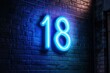 © Space Priest - Neon number 18 glowing on brick wall with blue light ambiance
