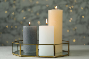 Wall Mural - Beautiful burning candles on light table against blurred lights