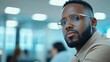 © Babycrab - A man with glasses and a beard gazes thoughtfully in an office setting.