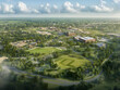 © Emons - Real estate picture birds eye view neighborhood - Aerial view of a landscaped area with buildings, greenery, and recreational spaces.