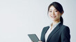 © sid - プロフェッショナルな笑顔の日本人ビジネスウーマンがタブレットを片手に白い背景に立つ
