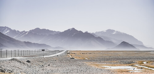 Wall Mural - Asphalt road of the Pamir Highway in the valley of the Tien Shan Mountains in Tajikistan in the Pamirs, landscape in the high desert mountains for background